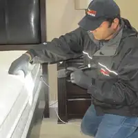 Bed bug inspection technician checking a mattress and bed frame for signs of infestation in Kansas City, MO