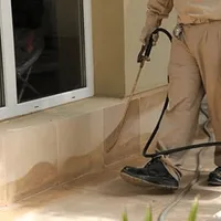 General pest control technician spraying exterior perimeter around a home in Kansas City, MO