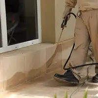 General pest control technician spraying exterior perimeter around a home in Kansas City, MO