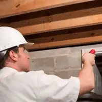 Termite inspection technician checking a basement wall and framing for termite activity in Kansas City, MO